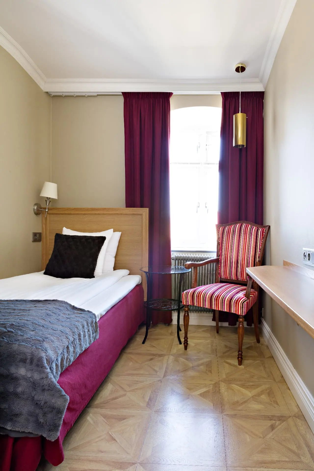 Enkelrum på Hotel Vasa med vinröda textilier och mässingspendel